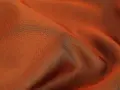 Pomarańczowy materiał, przypominający jedwab, to triacetat. Jest to syntetyczne włókno celulozowe, cenione za połysk i gładkość.