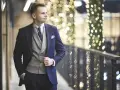 Elegancki mężczyzna w granatowym garniturze, szarej kamizelce i krawacie. Idealny męski strój koktajlowy na wieczorne wyjście.