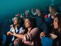Uśmiechnięci ludzie w kinie, jedzący popcorn. Wygodne ubrania to klucz do tego, jak się ubrać do kina, by czuć się swobodnie.