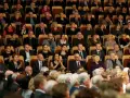 Elegancko ubrani ludzie siedzą w filharmonii, gotowi na koncert. Wskazówka, jak ubrać się do filharmonii: klasyka i szyk.