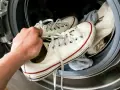 Ręka wkłada białe trampki do pralki. Dowiedz się, jak wyczyścić białe trampki, aby znów wyglądały jak nowe.
