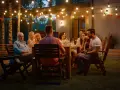 Rodzinne spotkanie przy grillu, przy świetle girland. Wszyscy ubrani swobodnie, idealnie na garden party dress code.