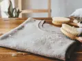 Delikatny sweter z kaszmiru, na którym widać mechacenie. Dłoń trzyma szczotkę do ubrań, gotową do usunięcia kuleczek.