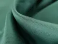 Gładka, zielona tkanina tencel, co to za materiał? Miękki, lejący się materiał z widocznym drobnym splotem.