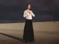Elegancka bomberka stylizacje z długą czarną spódnicą. Kobieta pozuje na tle burzowego nieba.