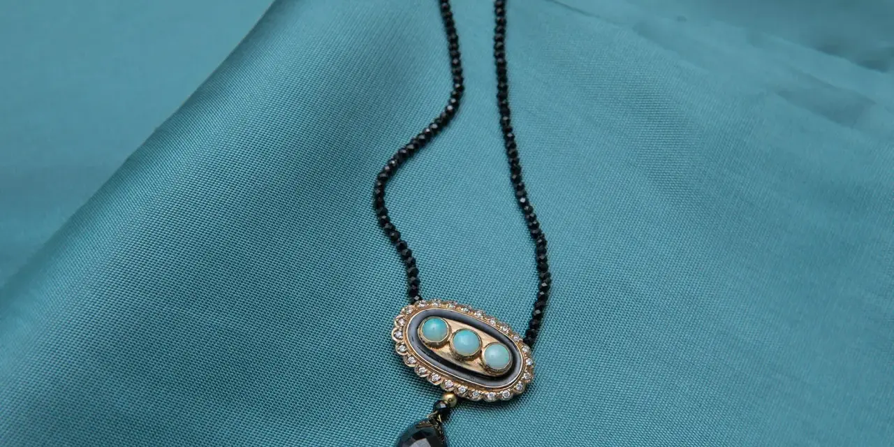 Elegancki naszyjnik z czarnego spinelu, ozdobiony owalnym medalionem z trzema niebieskimi kamieniami i wiszącą, czarną łezką.