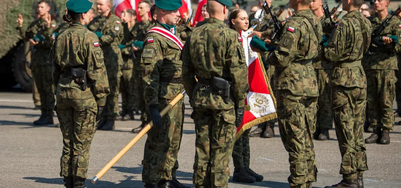 Żołnierze w mundurach polowych, zielonych beretach i z biało-czerwonymi flagami. To inspiracja, jak się ubrać na przysięgę wojskową.