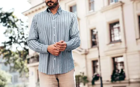 Mężczyzna w pasiowanej koszuli i beżowych spodniach. Stylizacja: koszula w spodnie czy nie? Elegancko i swobodnie.