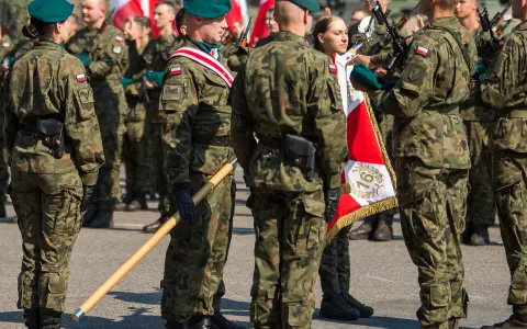 Żołnierze w mundurach polowych, zielonych beretach i z biało-czerwonymi flagami. To inspiracja, jak się ubrać na przysięgę wojskową.