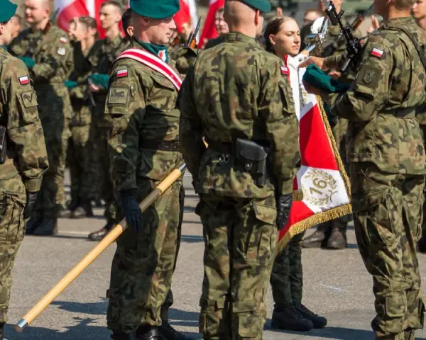 Żołnierze w mundurach polowych, zielonych beretach i z biało-czerwonymi flagami. To inspiracja, jak się ubrać na przysięgę wojskową.