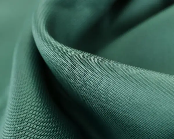 Gładka, zielona tkanina tencel, co to za materiał? Miękki, lejący się materiał z widocznym drobnym splotem.