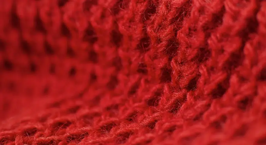Czerwony, miękki materiał z widocznym splotem. Czy to angora? Co to jest angora? To delikatna wełna.