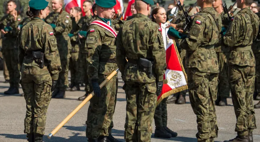 Żołnierze w mundurach polowych, zielonych beretach i z biało-czerwonymi flagami. To inspiracja, jak się ubrać na przysięgę wojskową.