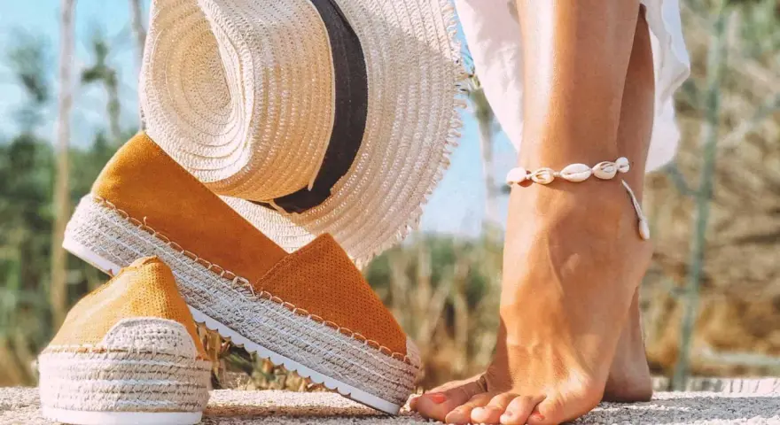 Letnie espadryle w kolorze musztardowym i słomkowy kapelusz. Dowiedz się, jak wyczyścić espadryle, by służyły Ci przez lata.