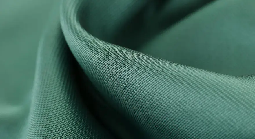 Gładka, zielona tkanina tencel, co to za materiał? Miękki, lejący się materiał z widocznym drobnym splotem.