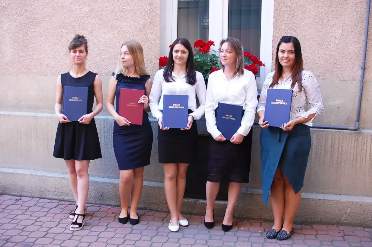 Pięć kobiet w eleganckich strojach, trzymających prace magisterskie. To inspiracja, jak się ubrać na obronę, nawet jeśli jesteś mężczyzną i chcesz wyglądać profesjonalnie.